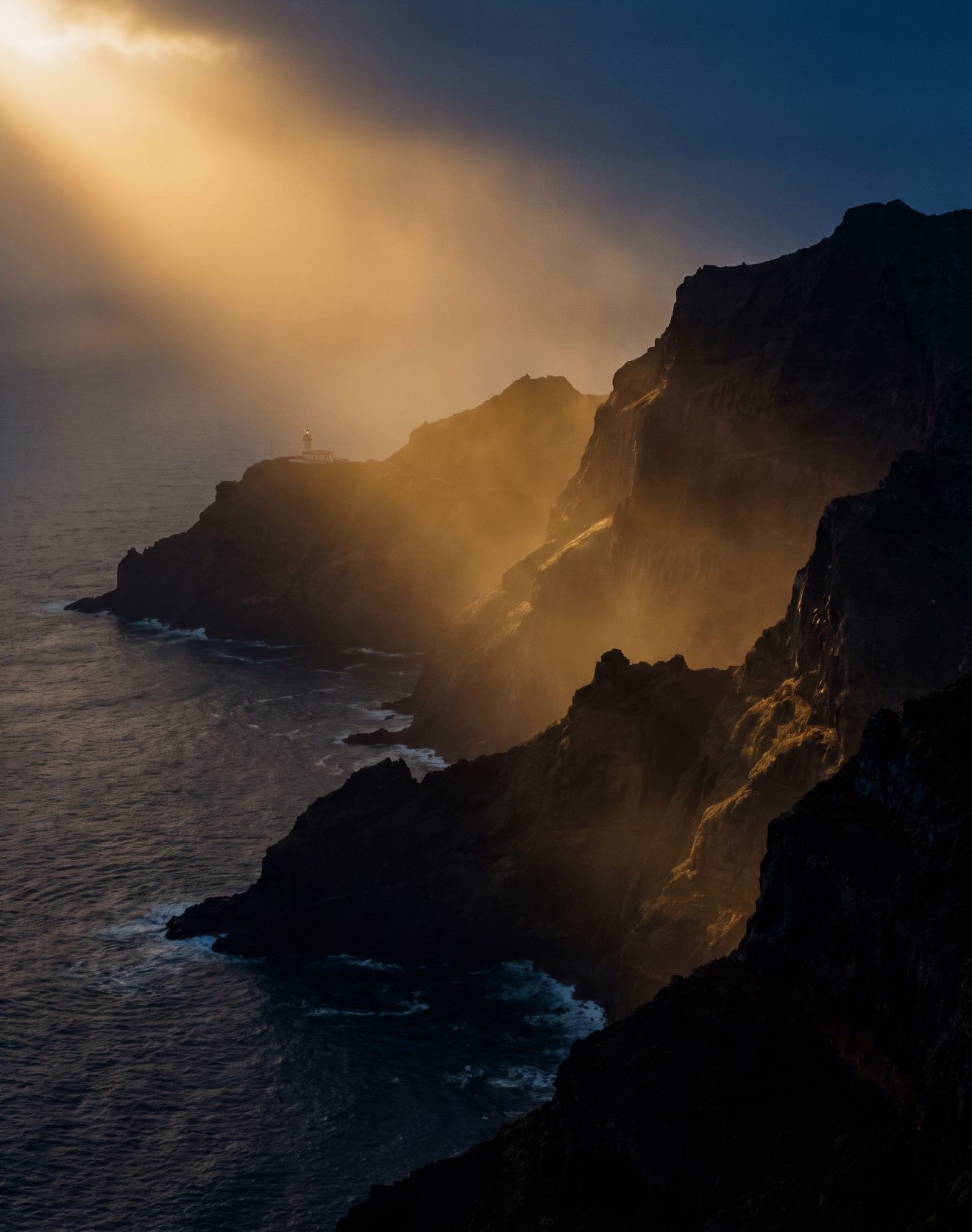 Madeira's north-coast cliffs at dusk, lit by a beam of golden light